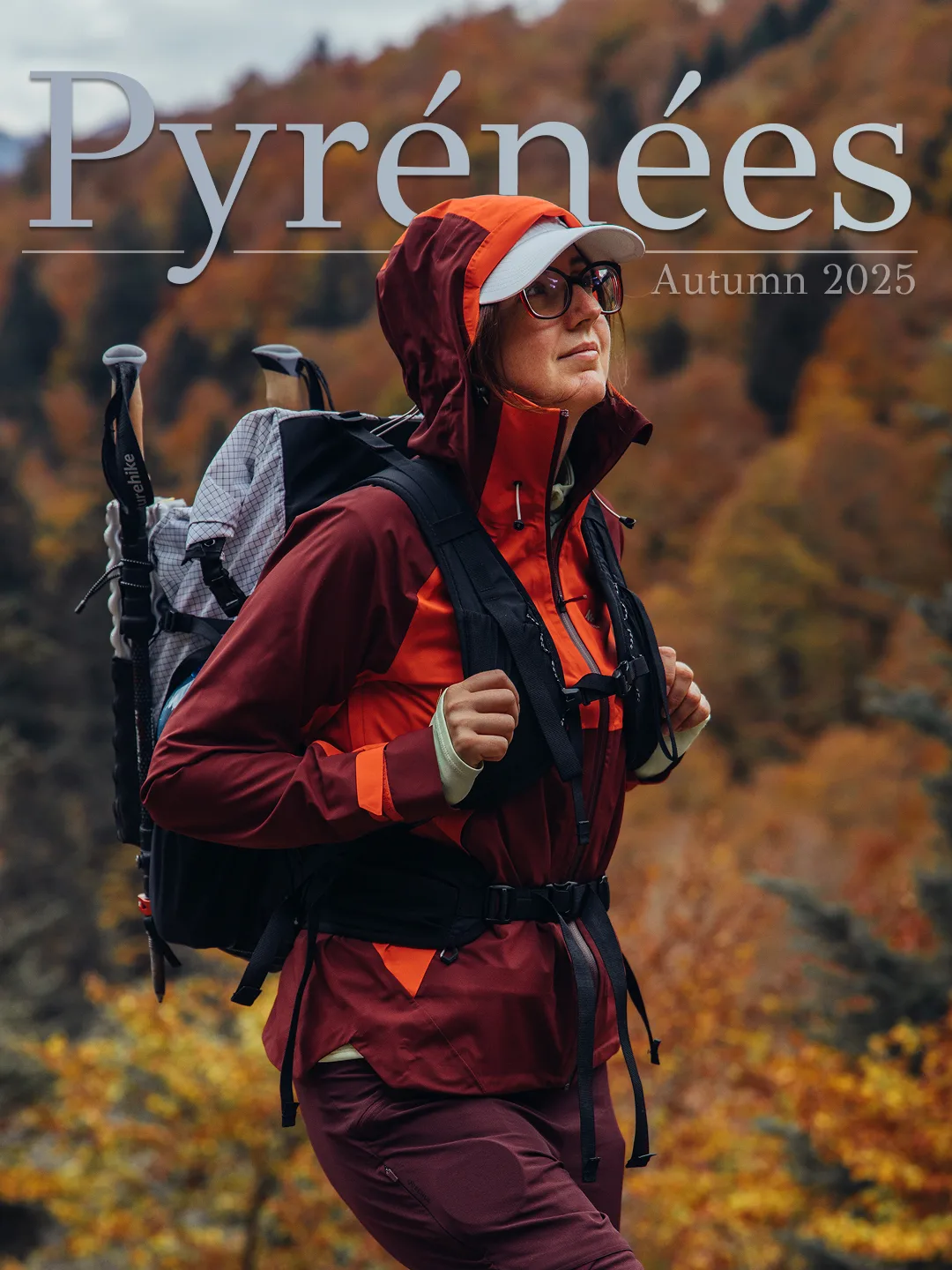 Hiker in red rain gear beneath limestone cliffs in the autumn Pyrenees