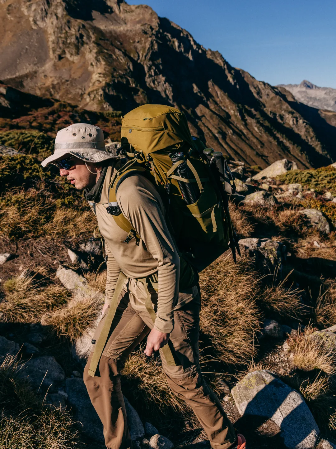 Hiker carrying an olive Deuter backpack above a mountain valley