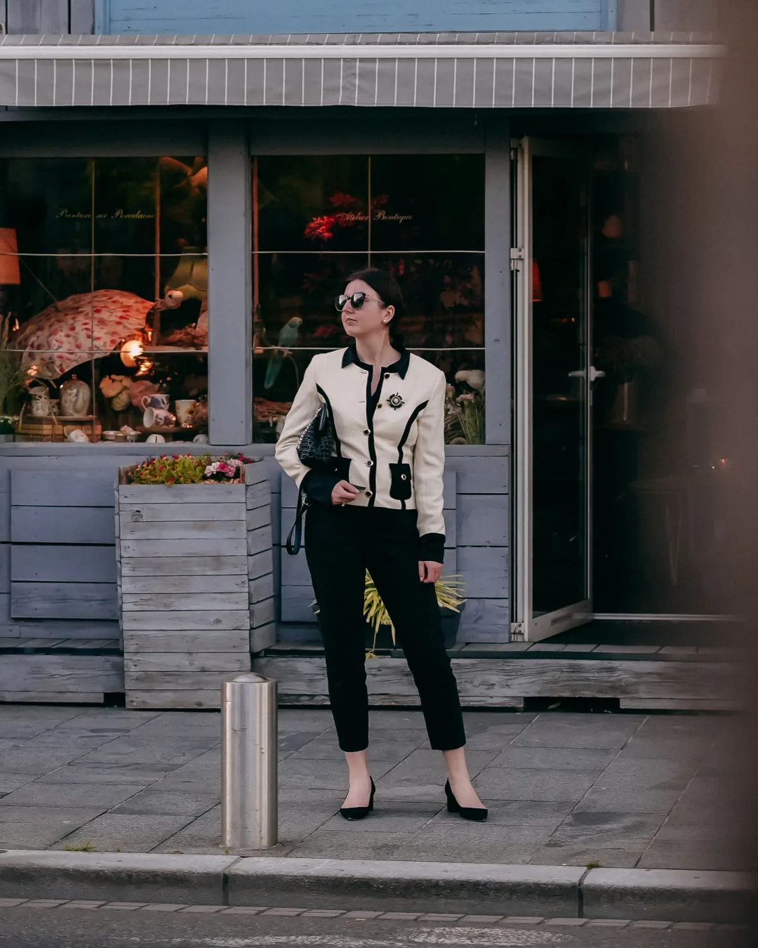 Woman in a black-and-white jacket posing outside a city boutique