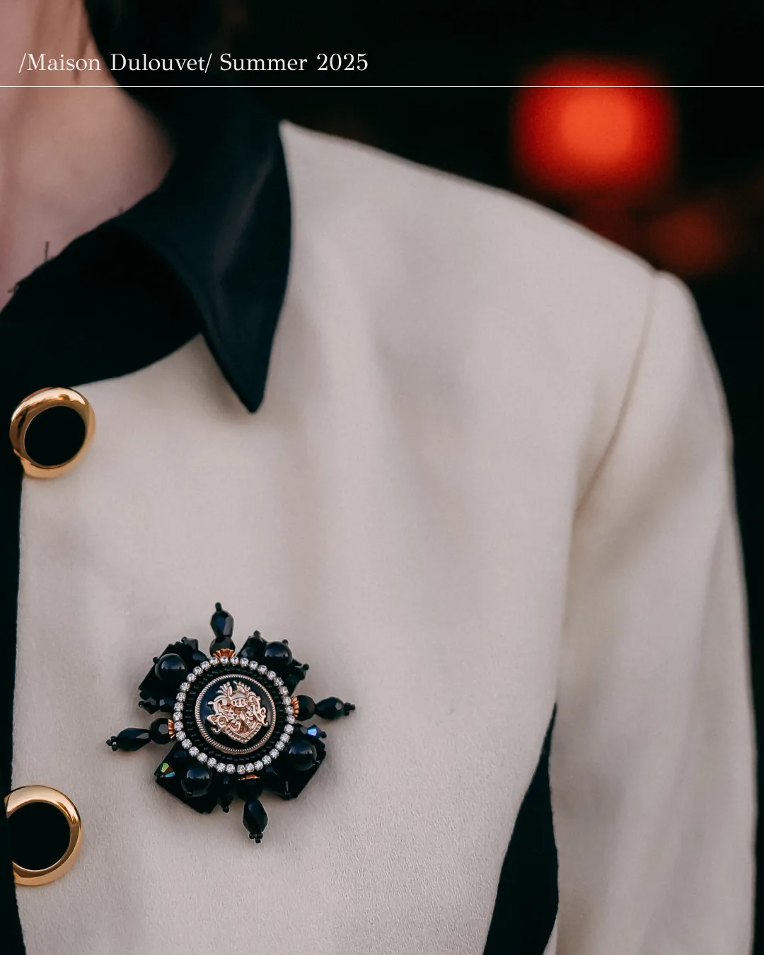 Broche floral Dulouvet sobre una chaqueta blanca y negra