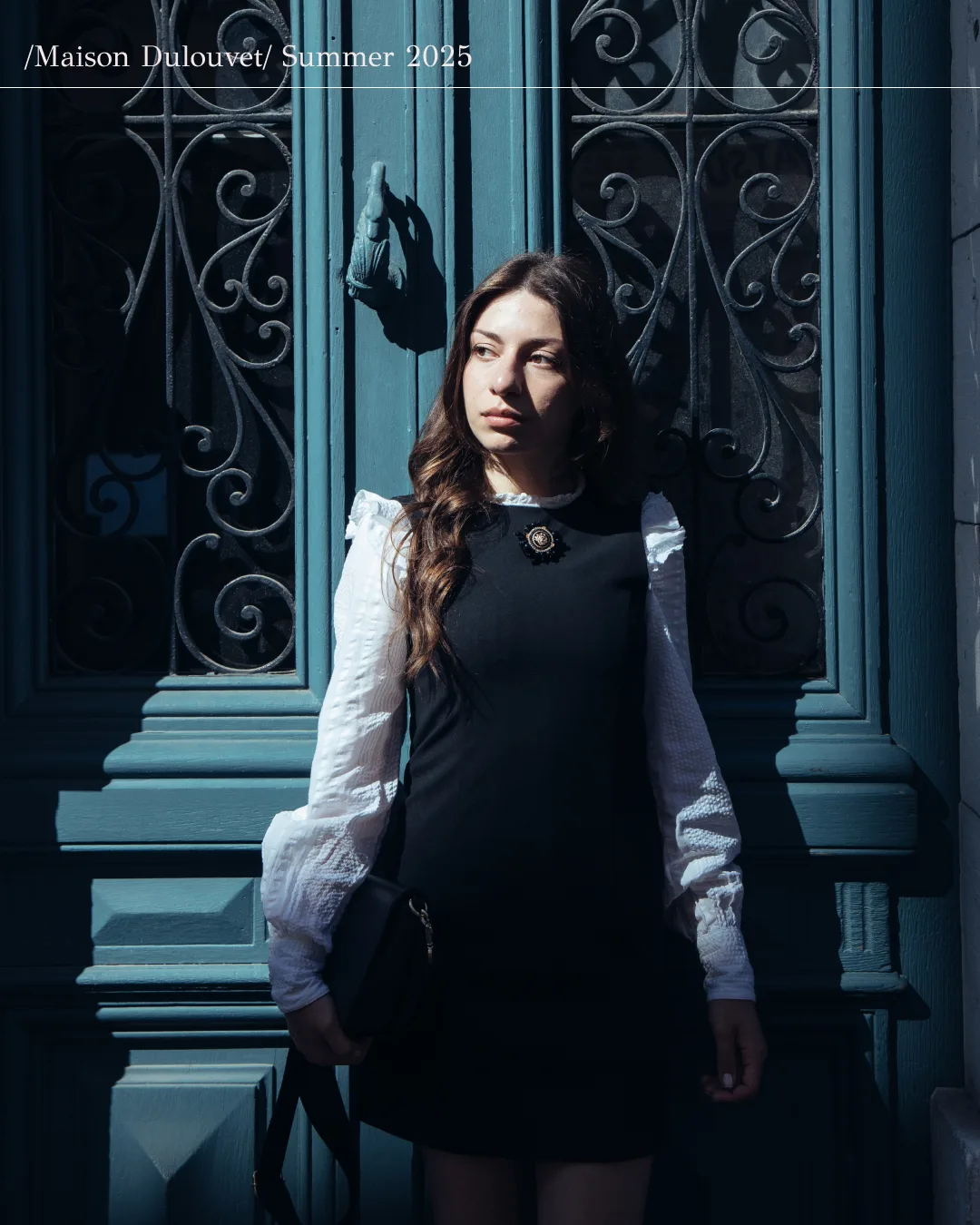 Femme portant des bijoux Dulouvet devant une porte bleue
