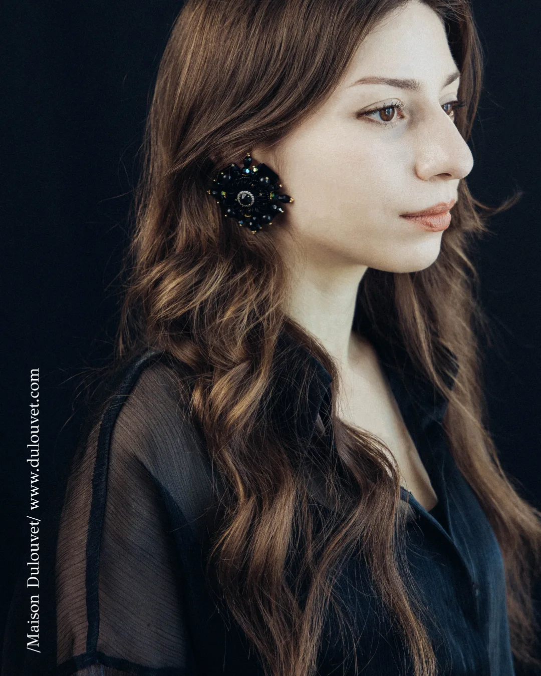 Portrait of a woman wearing a black floral Dulouvet statement earring
