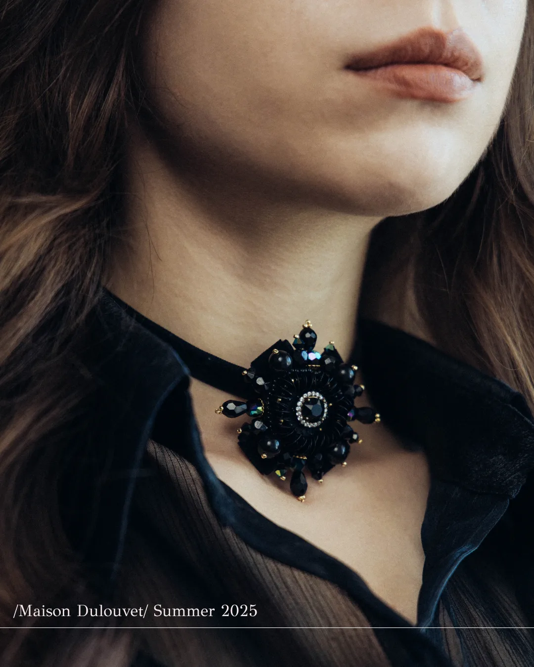 Collier floral noir Dulouvet porté sur un chemisier noir