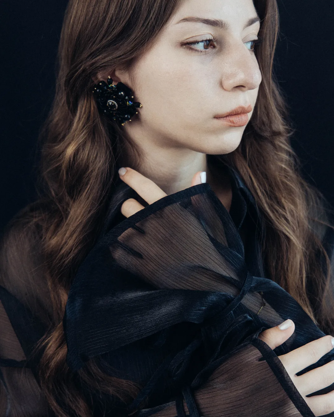 Femme en chemisier noir portant une boucle d’oreille Dulouvet