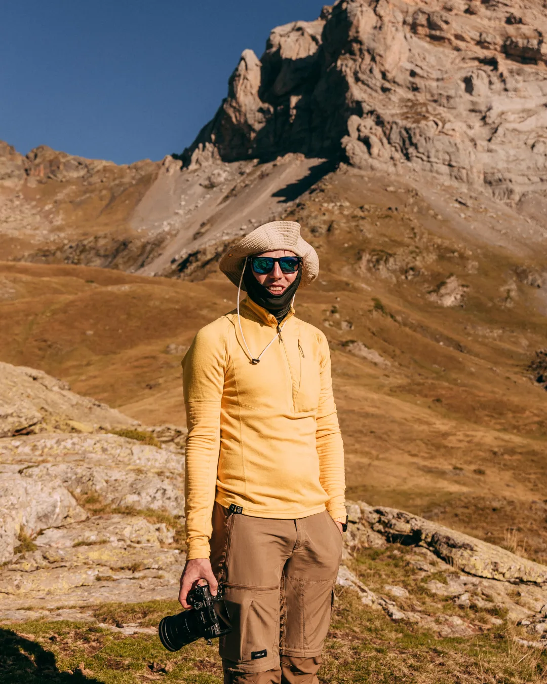 Senderista de amarillo bajo una cresta rocosa de los Pirineos