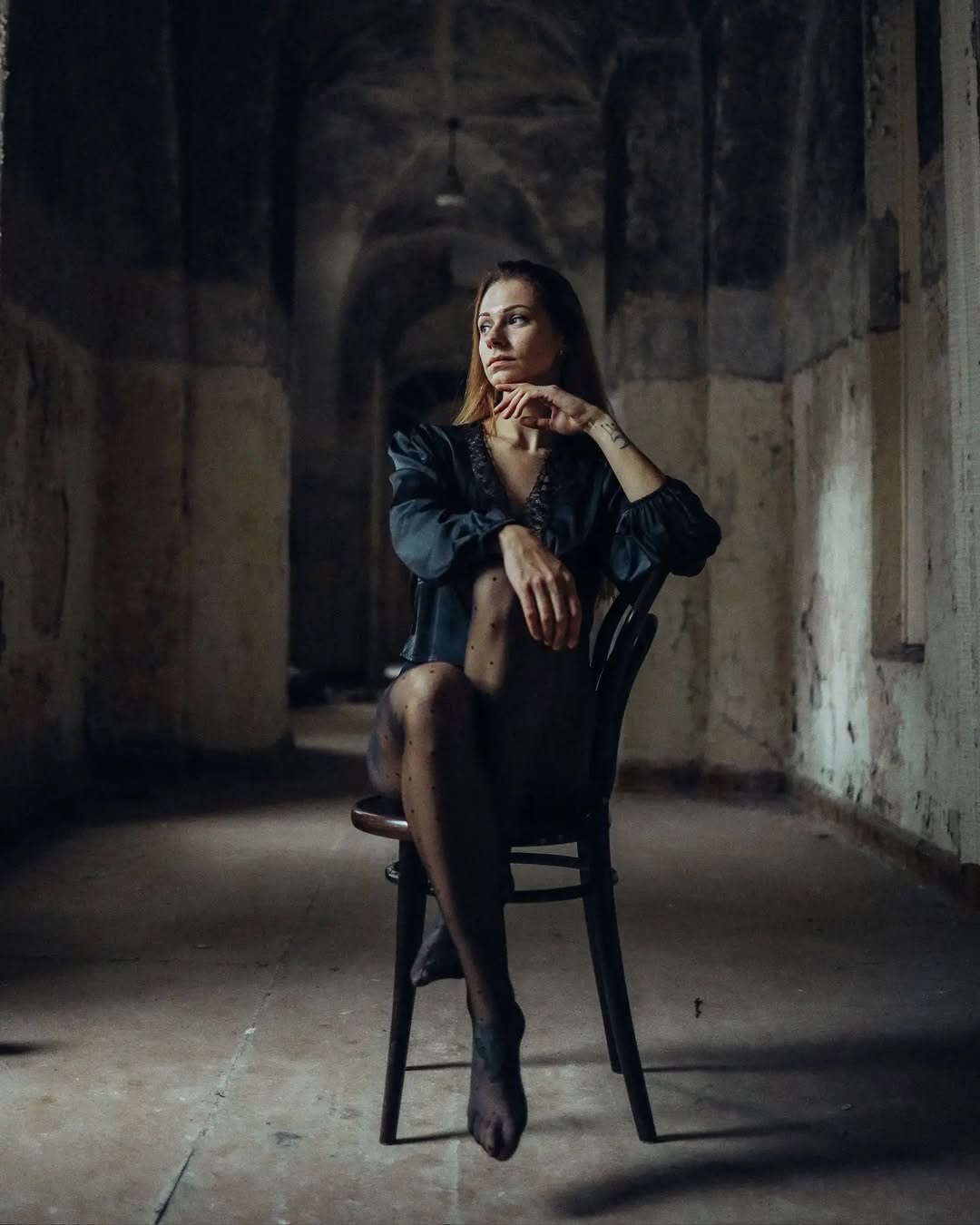 Woman seated on a chair in a softly lit industrial interior