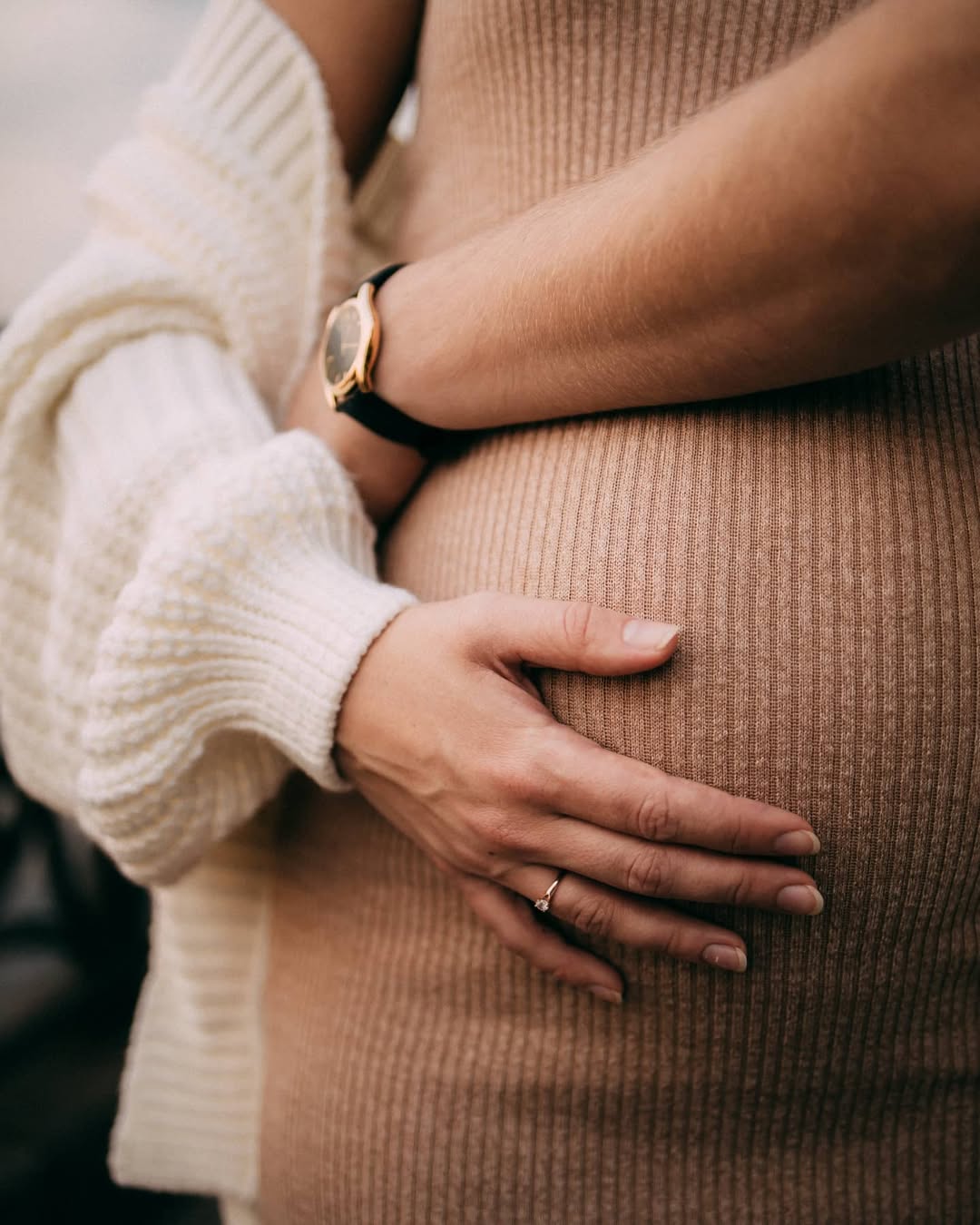 Primer plano de unas manos apoyadas con ternura sobre un vientre de embarazo